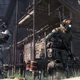 A Pilot dashes past a Titan while crading an assault rifle in his arms. The massive machine aims its own weapon over the Pilot's shoulder.